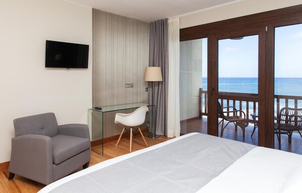 Una habitación de hotel con cama, escritorio, silla, televisión y balcón con sillas.