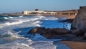 A coastal hotel with a beach view, rocky shoreline, and a clear sky. - El Mirador de Fuerteventura (Puerto del Rosario)