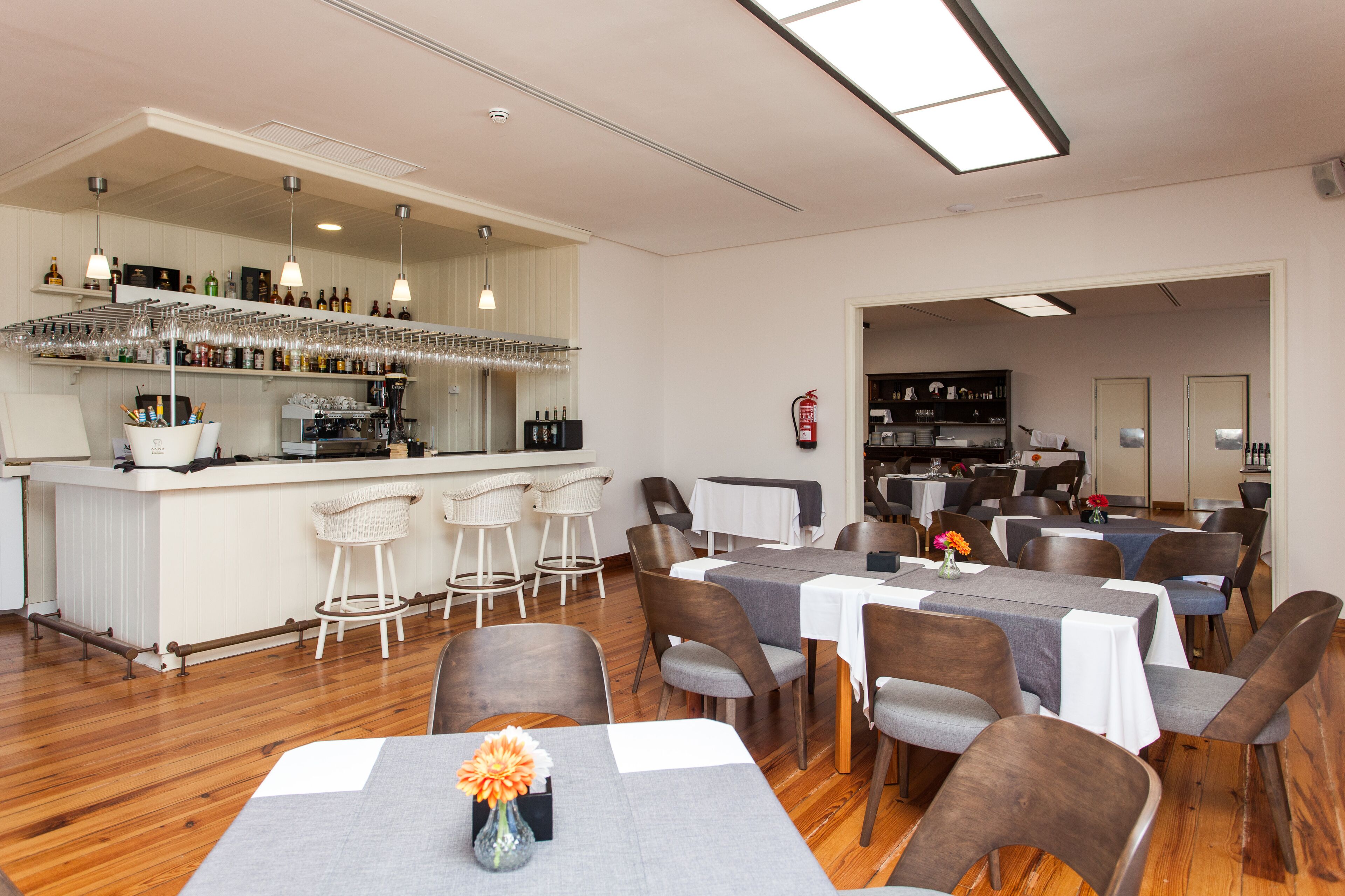 Un restaurant amb zona de bar, diverses taules i cadires.