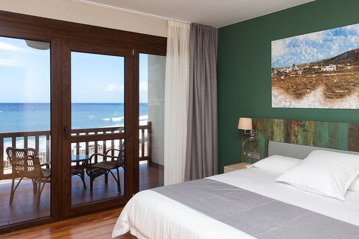 Une chambre d’hôtel avec un balcon, un lit et un tableau au mur.