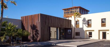 A modern building with a wooden facade and a separate tower with a balcony.