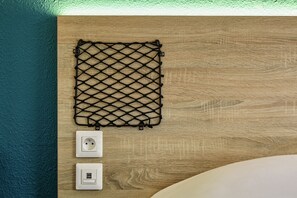A wooden wall with a black netted object and two white electrical outlets. - hotelF1 Paris Gennevilliers (Gennevilliers)