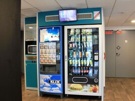 Máquina expendedora con diversas opciones de bocadillos y bebidas, como papas fritas y refrescos.