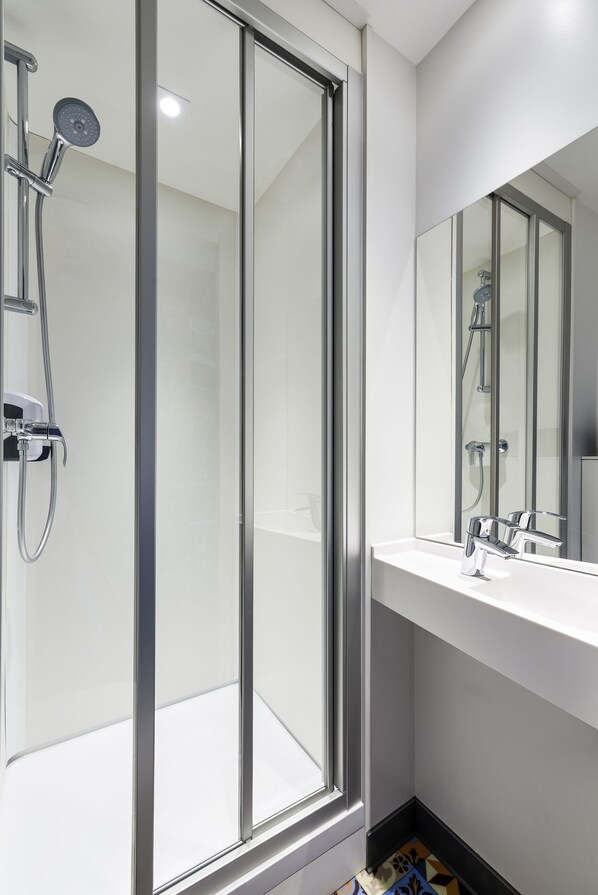 A modern bathroom with a glass-enclosed shower, a white sink, and a large mirror. - hotelF1 Paris Gennevilliers (Gennevilliers)