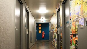 A hallway with doors on both sides, a blue wall at the end, and a fire extinguisher on the wall. - hotelF1 Paris Gennevilliers (Gennevilliers)