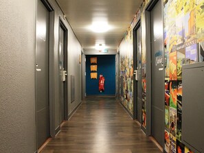 A hallway with doors on both sides, a blue wall at the end, and a fire extinguisher on the wall.