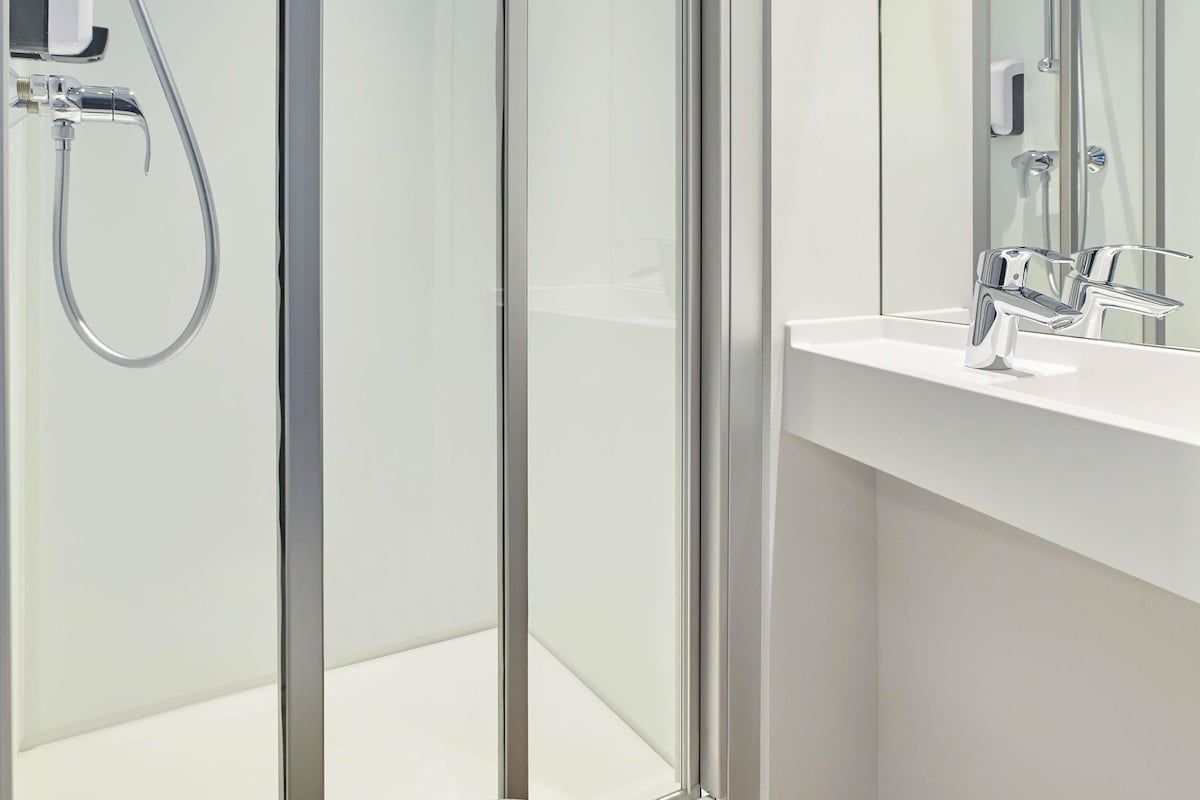 Un baño moderno con cabina de ducha de vidrio, un lavabo blanco y un espejo.