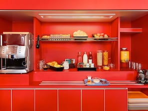 A red-themed breakfast bar with a coffee machine, bread, pastries, and various breakfast items. - hotelF1 Paris Gennevilliers (Gennevilliers)