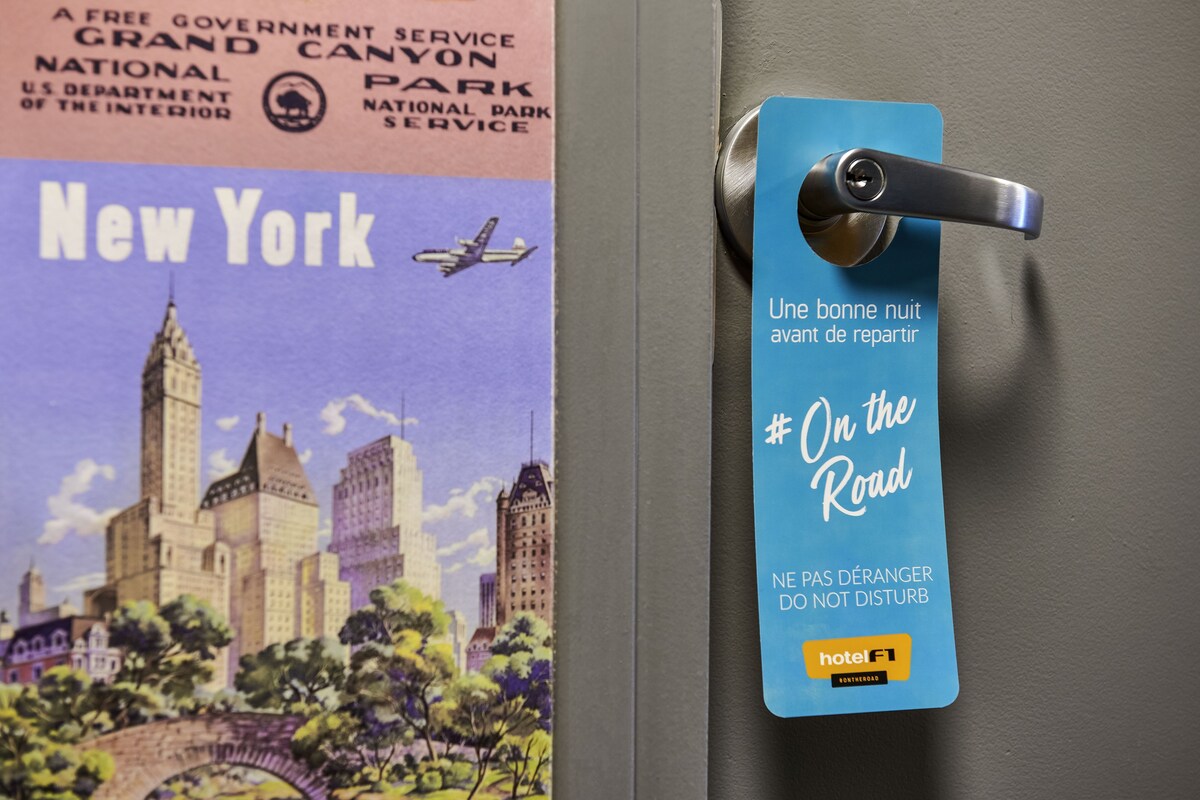 A door with a blue hotel tag that reads "On the Road" and "NE PAS DÉRANGER DO NOT DISTURB" in French.