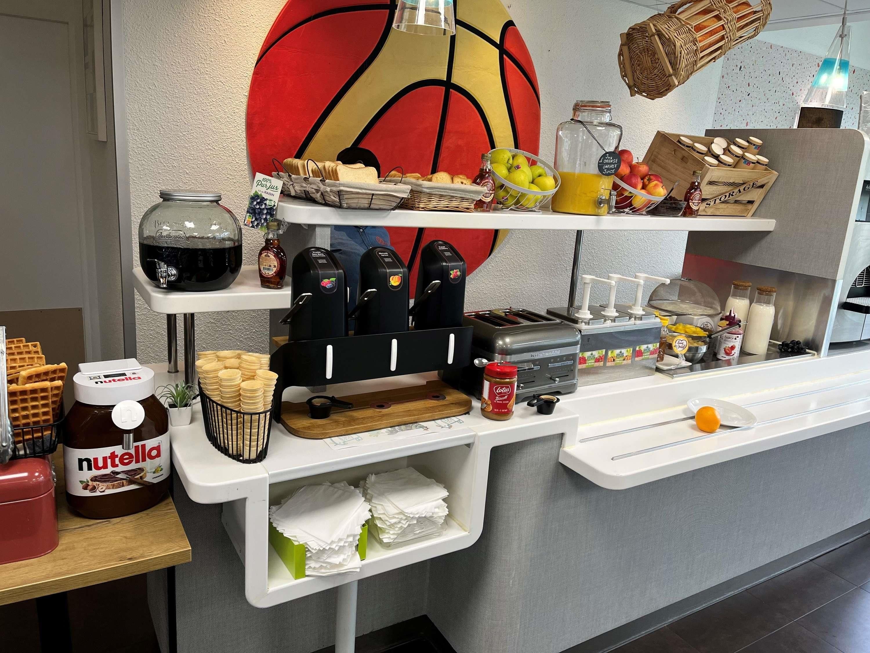 A breakfast bar with various food items, including waffles, Nutella, and juice dispensers.