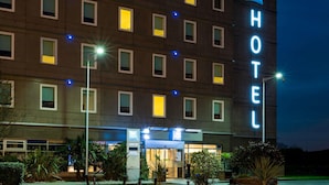 Een hotel met meerdere verdiepingen, verlichte ramen en een opvallend 'HOTEL'-bord.