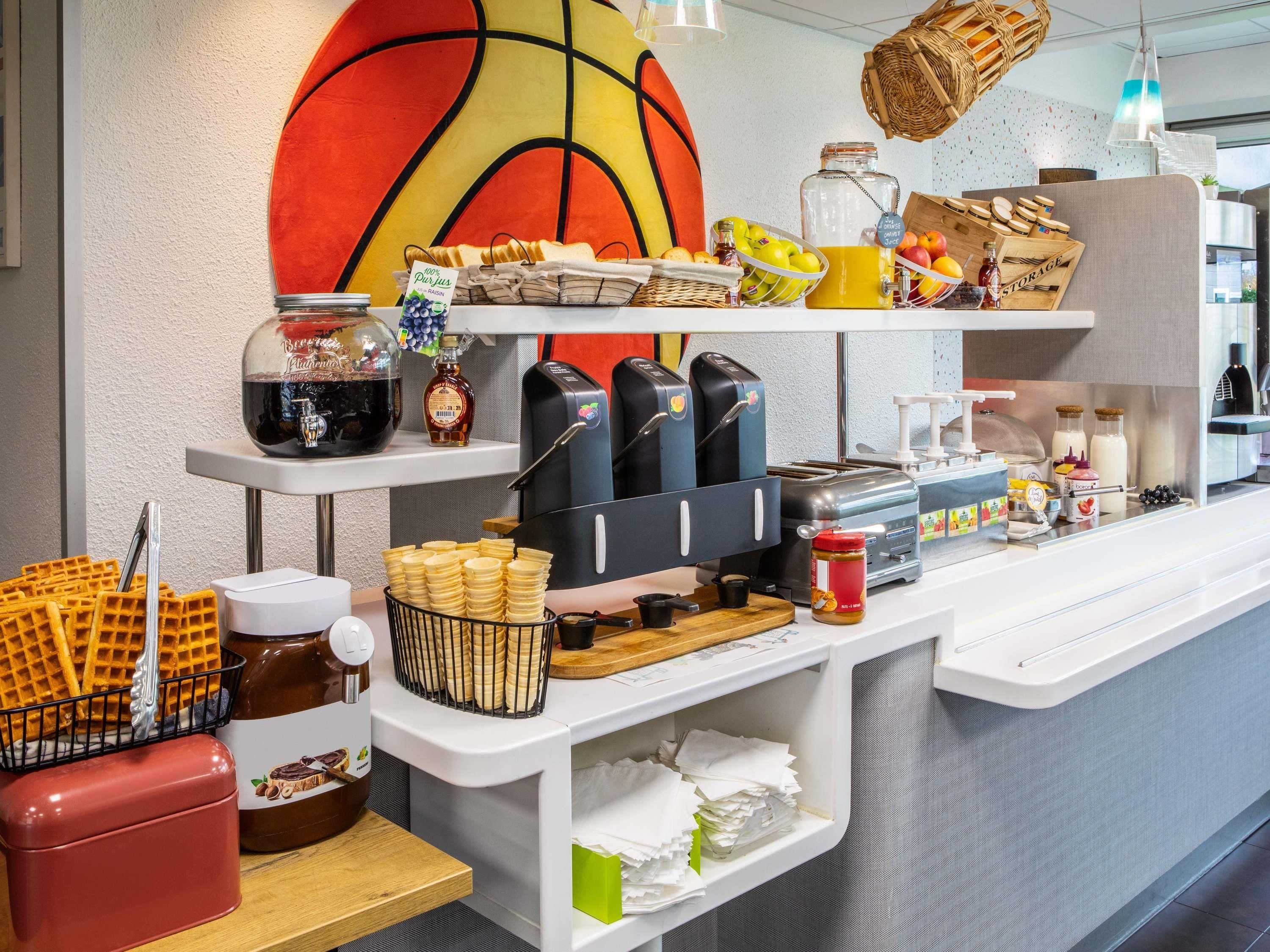 A breakfast bar with waffles, coffee machines, and various condiments.