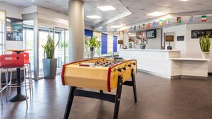 Een lobby met een tafelvoetbaltafel, een receptiebalie en een bar met krukken.
