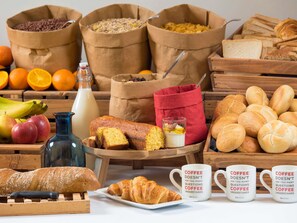 A breakfast spread with bread, pastries, fruits, and coffee mugs. - ibis budget Roissy CDG Paris Nord 2 (Roissy-en-France)