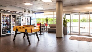 Een hal met een pooltafel, automaten, een bank en een groot raam.