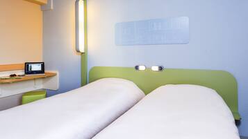 A hotel room with two beds, a desk with a computer, and a wall-mounted light fixture.