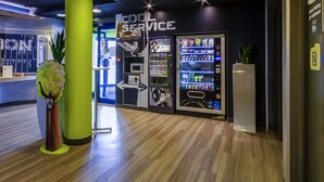 Un interior moderno con una zona de recepción, un quiosco de servicios y máquinas expendedoras.