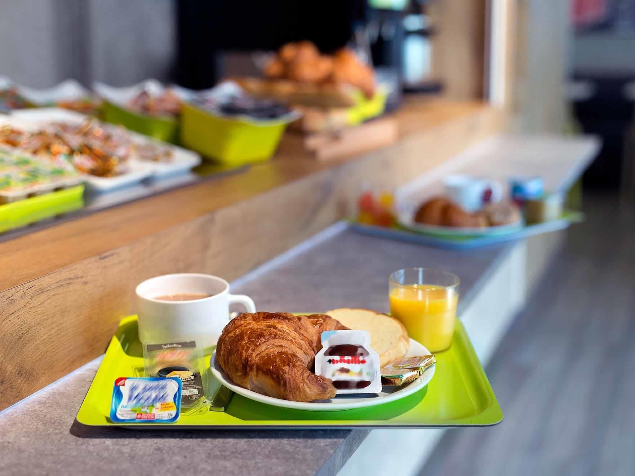 A breakfast buffet with croissants, juice, and coffee on trays.