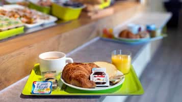A breakfast buffet with croissants, juice, and coffee on trays.