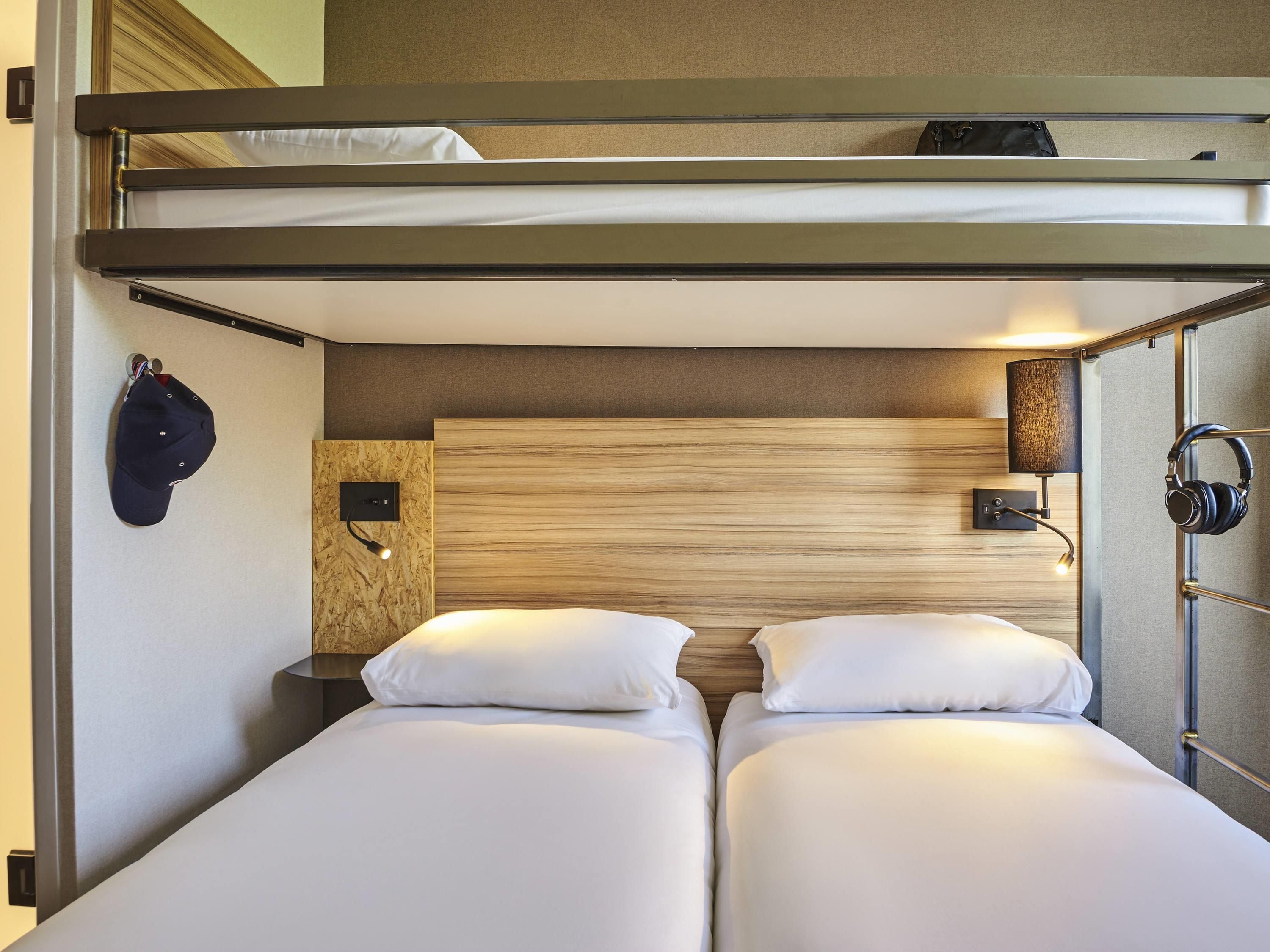 Une chambre avec un lit superposé, une tête de lit en bois, des lampes de chevet et un casque audio posé sur un support.