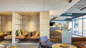 Un espace de détente moderne, doté de différents types de sièges, d’un bar et offrant une vue sur l’extérieur.
