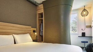 A hotel room with a large bed, a wooden headboard, a built-in wardrobe, a hanging light fixture, and a window with a view. - greet Hotel Paris porte de la Chapelle - Aréna (Paris)