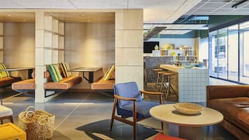 Un área de descanso moderna con diferentes disposiciones de asientos, un bar y vistas al exterior.