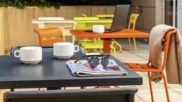 Une table avec un magazine, une paire de lunettes et deux tasses blanches.