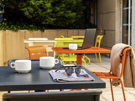 Una mesa con una revista, un par de gafas y dos tazas blancas.