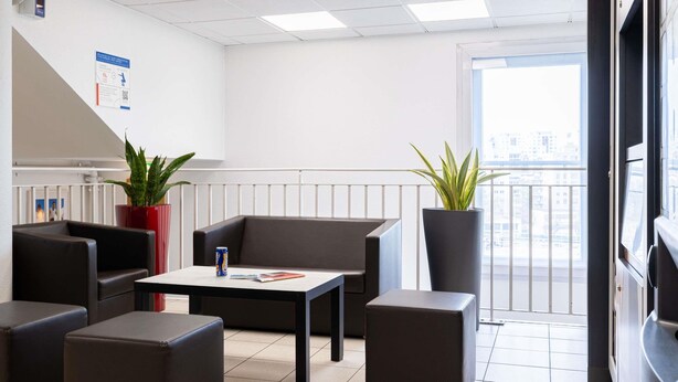 Un espace de bureau moderne comprenant un canapé, des fauteuils, une table et des plantes en pot.