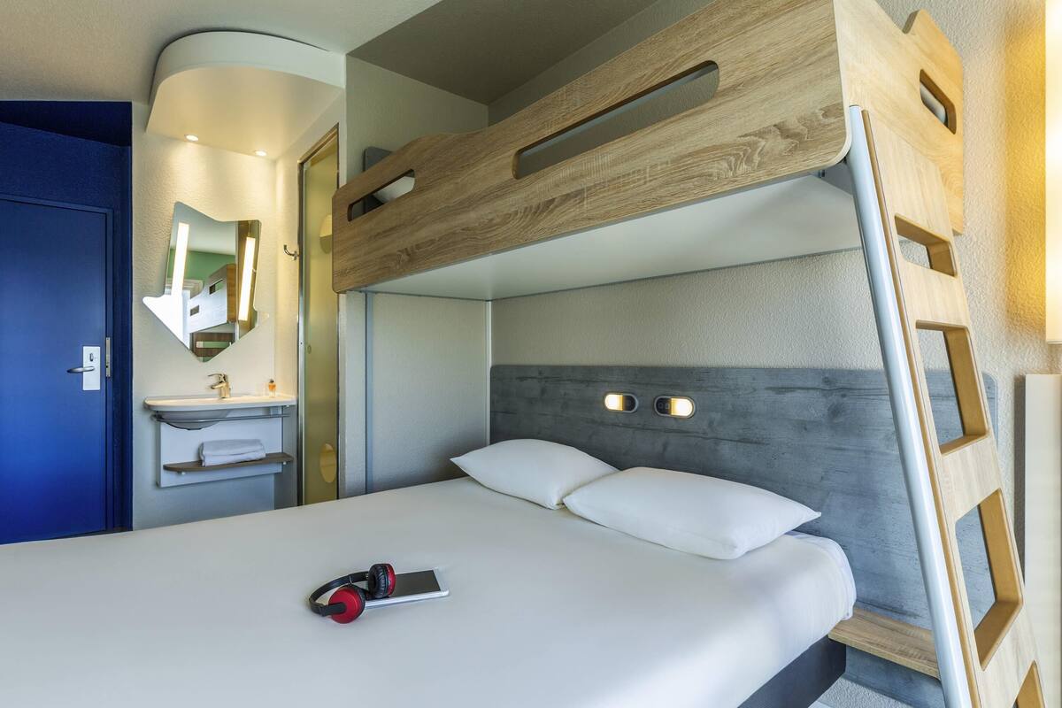 Ein Stockbett mit Holzkopfteil, ein Nachttisch und ein Spiegel.