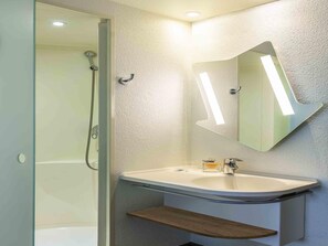 Ein modernes Badezimmer mit Duschkabine aus Glas, einem weißen Waschbecken mit Holzablage und einem Spiegel mit integrierter Beleuchtung.