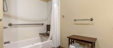 Un baño con bañera, ducha, toallero y una pequeña mesa con toallas.