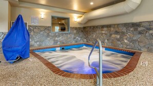 A spa area with a stone wall, a pool with a blue edge, and a covered bench.