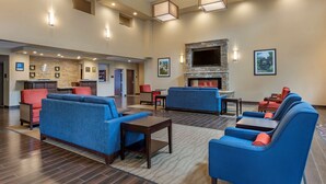 A spacious lobby with blue sofas and armchairs, a fireplace, and a reception desk.