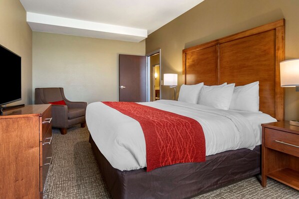 Una habitación de hotel con una cama grande, un escritorio, una silla, un televisor y un armario.