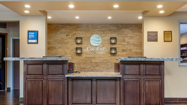 A reception area with a stone wall, a logo, and a sign indicating check-in times.
