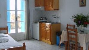 Una cocina compacta con armarios de madera, una hornilla pequeña y un comedor con mesa y sillas.