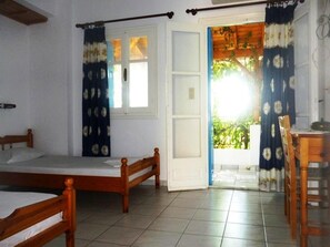 A room with two wooden beds, a desk, and a door leading to a balcony.