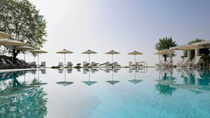 A pool with lounge chairs and umbrellas, surrounded by trees. - Olympios Zeus (Dio-Olympos)