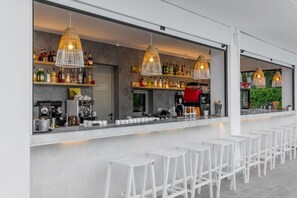 A bar area with white stools, hexagonal patterned walls, and hanging pendant lights. - Olympios Zeus (Dio-Olympos)