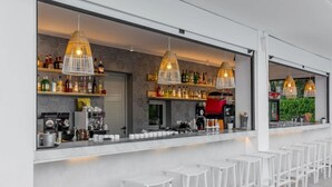 A bar area with white stools, hexagonal patterned walls, and hanging pendant lights. - Olympios Zeus (Dio-Olympos)