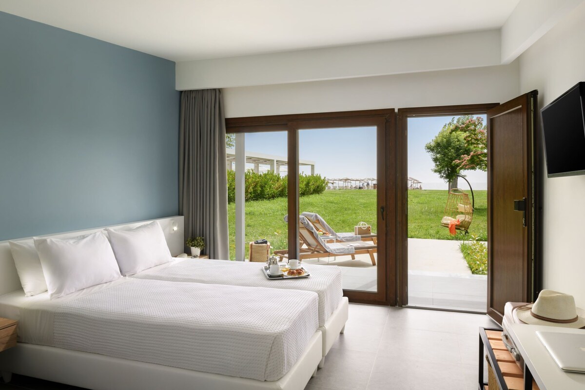 A hotel room with a bed, a desk, and a view of the outdoor area.