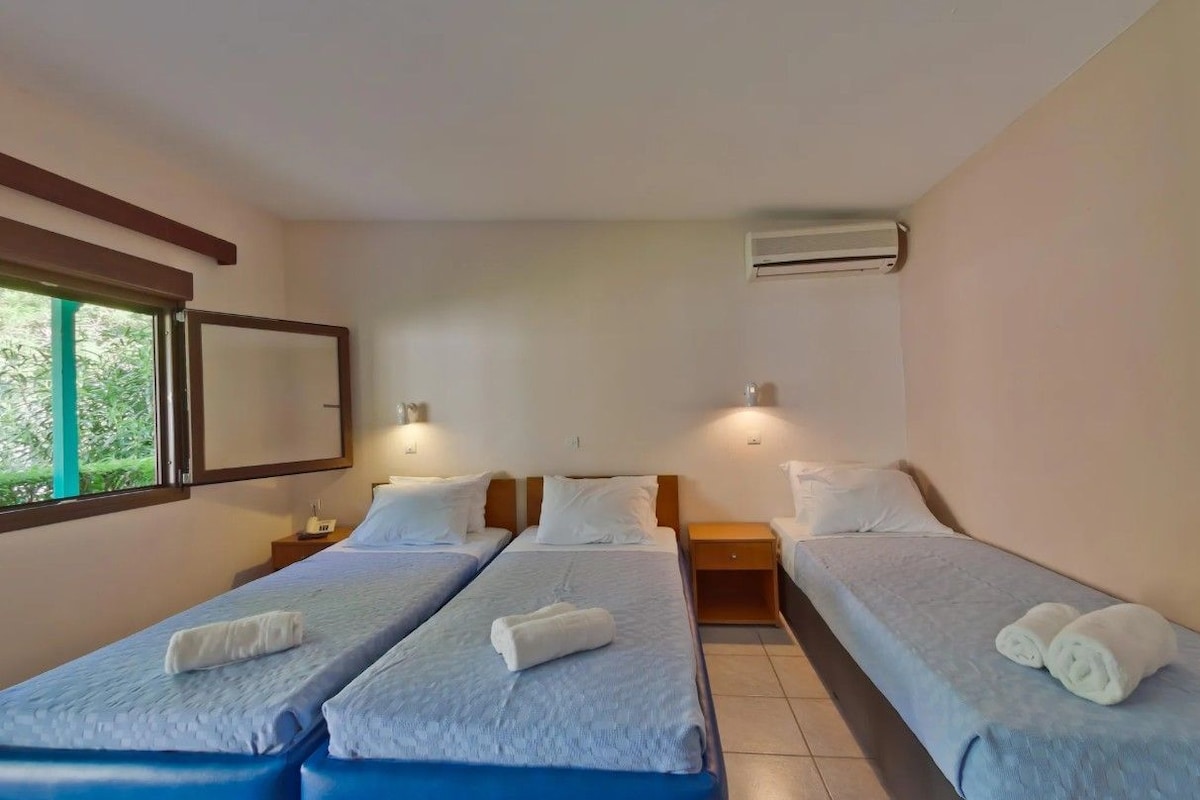 Ein Hotelzimmer mit zwei Einzelbetten, einem großen Fenster und einer Klimaanlage.