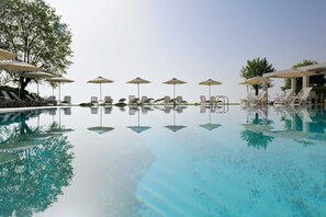 A pool with lounge chairs and umbrellas, surrounded by trees. - Olympios Zeus (Dio-Olympos)