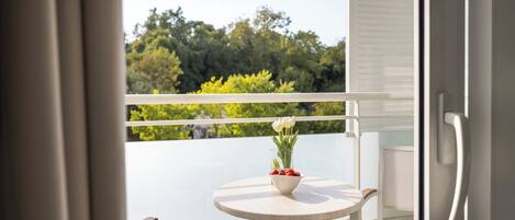 A balcony with a round table, a bowl of fruit, and a vase of flowers.