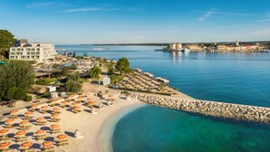 A coastal hotel with a beach, clear blue waters, and a marina. - Isabella Island Resort Valamar Collection 4 (Porec)