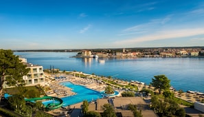 A resort with a large swimming pool, a water slide, and a view of the city across the water.