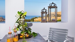 A balcony with a table, two lanterns, a potted plant, and bottles of orange juice.