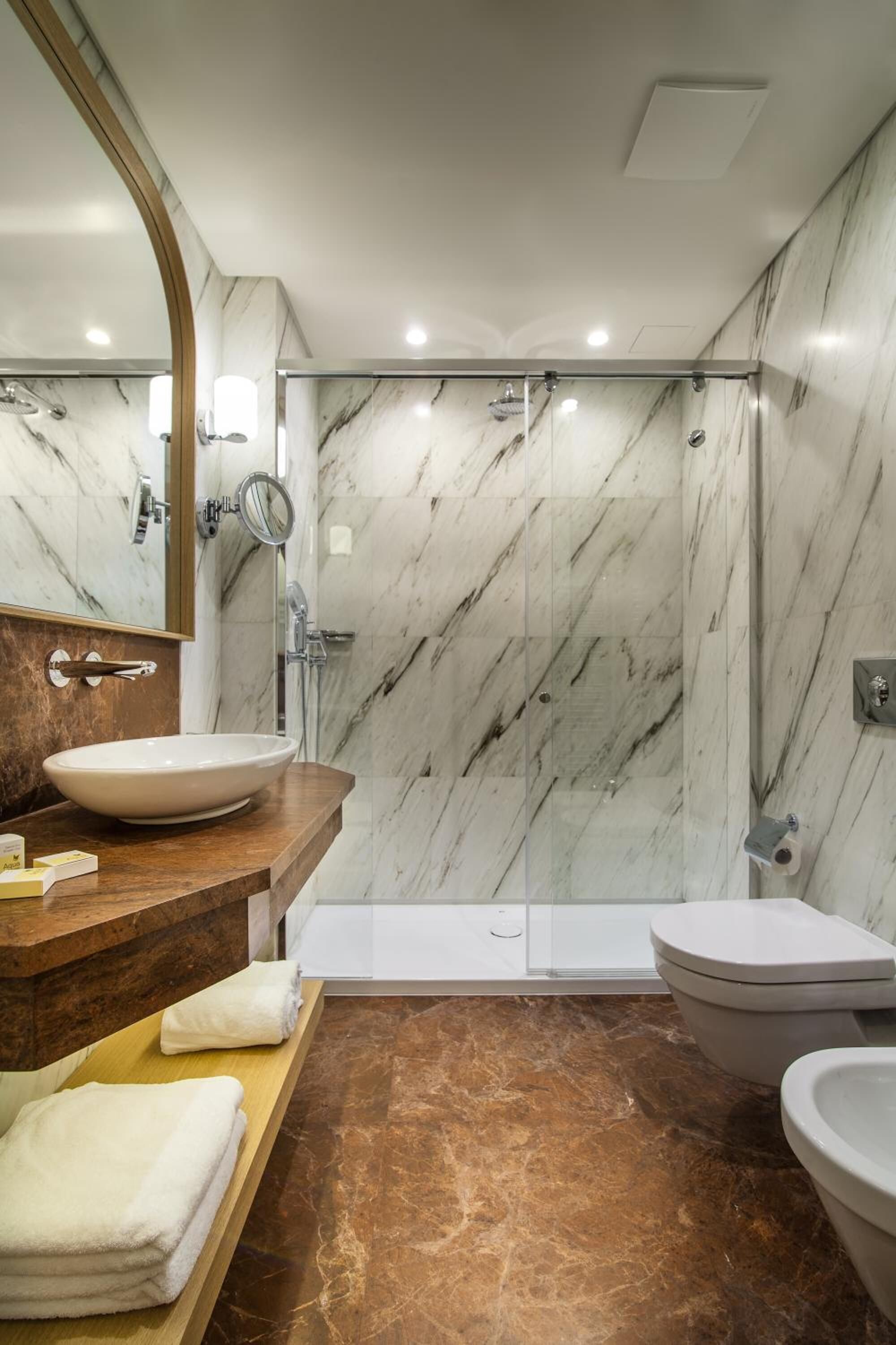 Une salle de bain moderne avec un meuble-lavabo en marbre, un grand miroir, une douche et des toilettes.